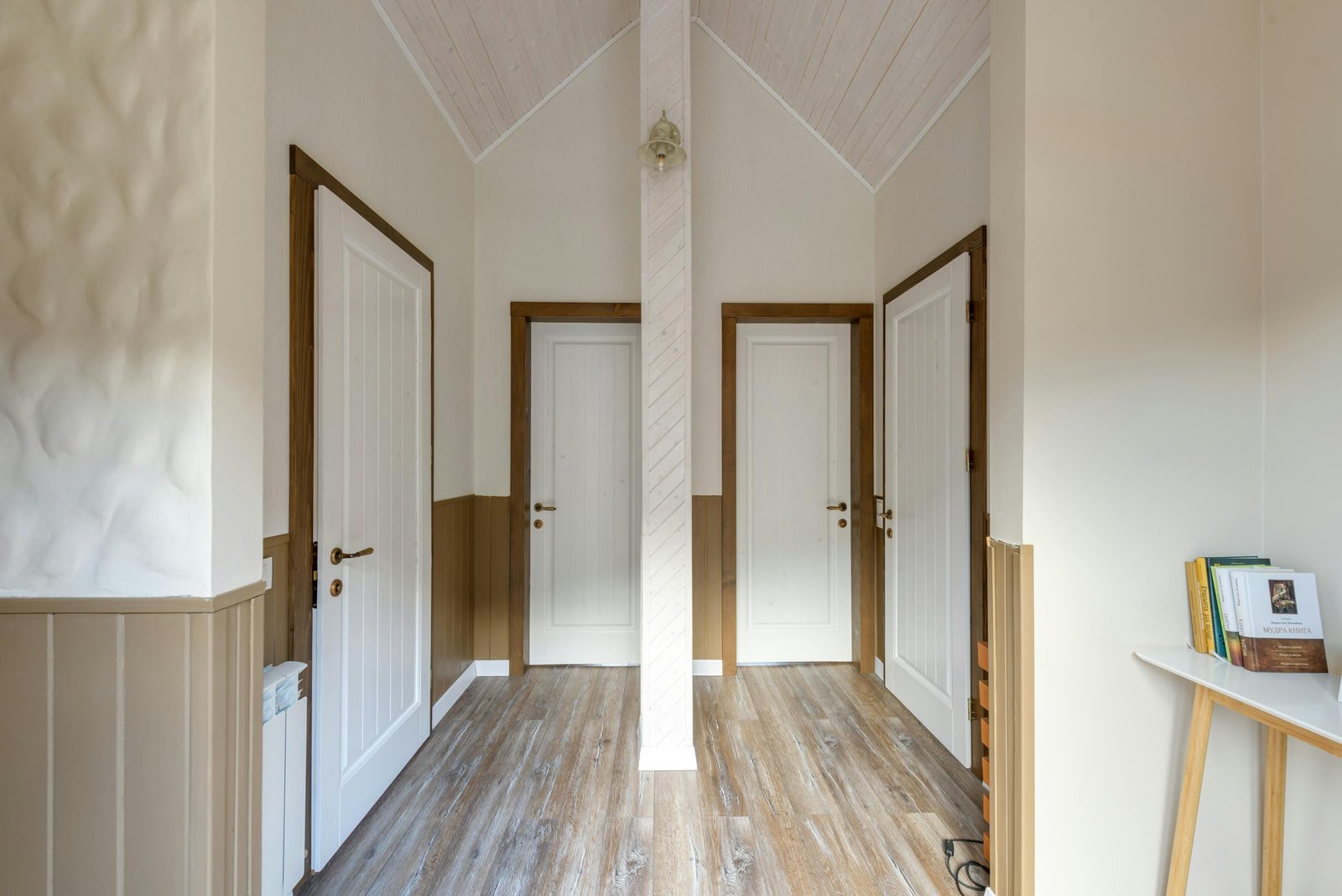 Bright hallway with wooden flooring and three doors, offering a cozy homey feel.