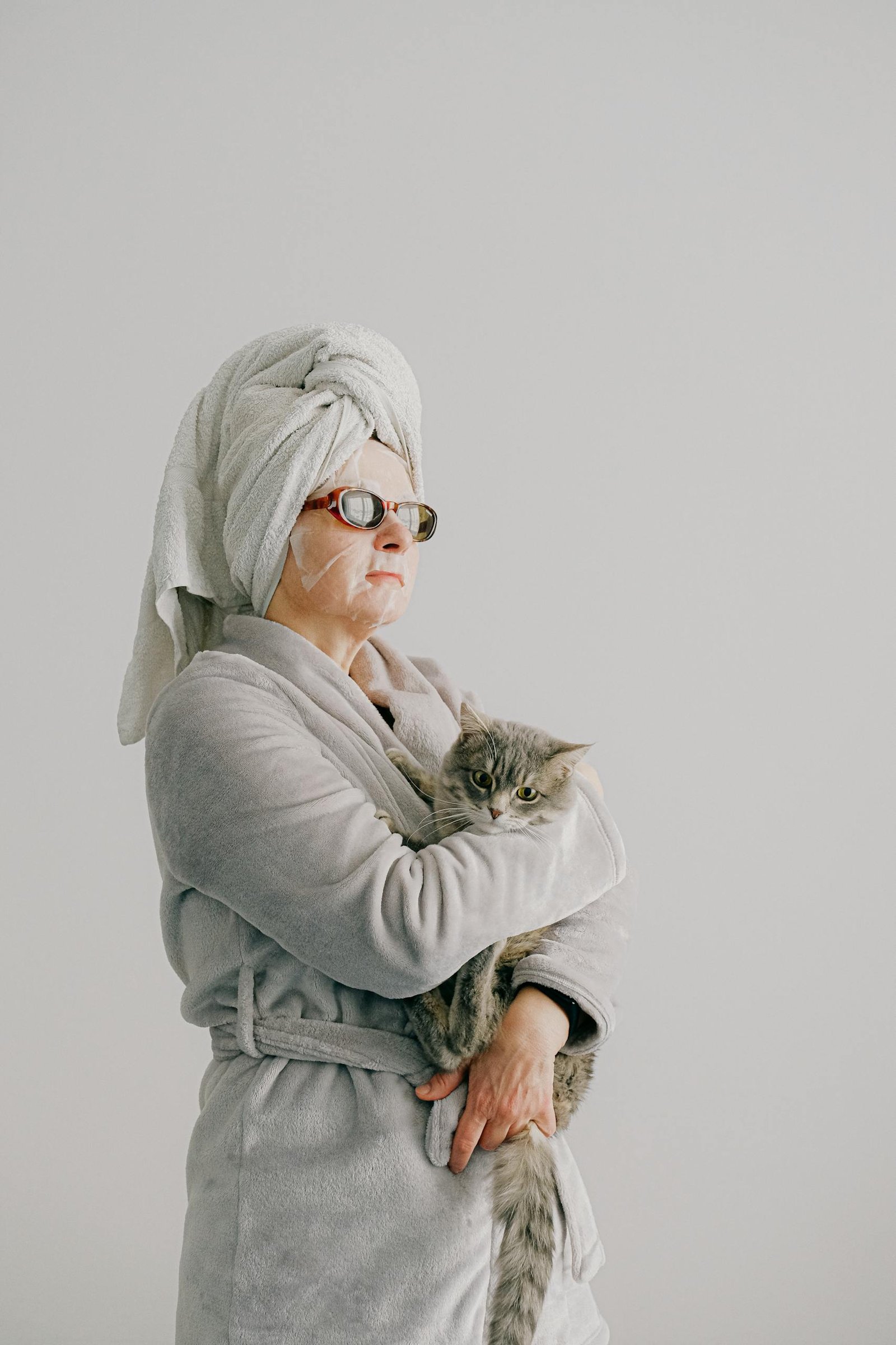 Woman in a bathrobe with a cat, representing relaxation and home spa vibes.