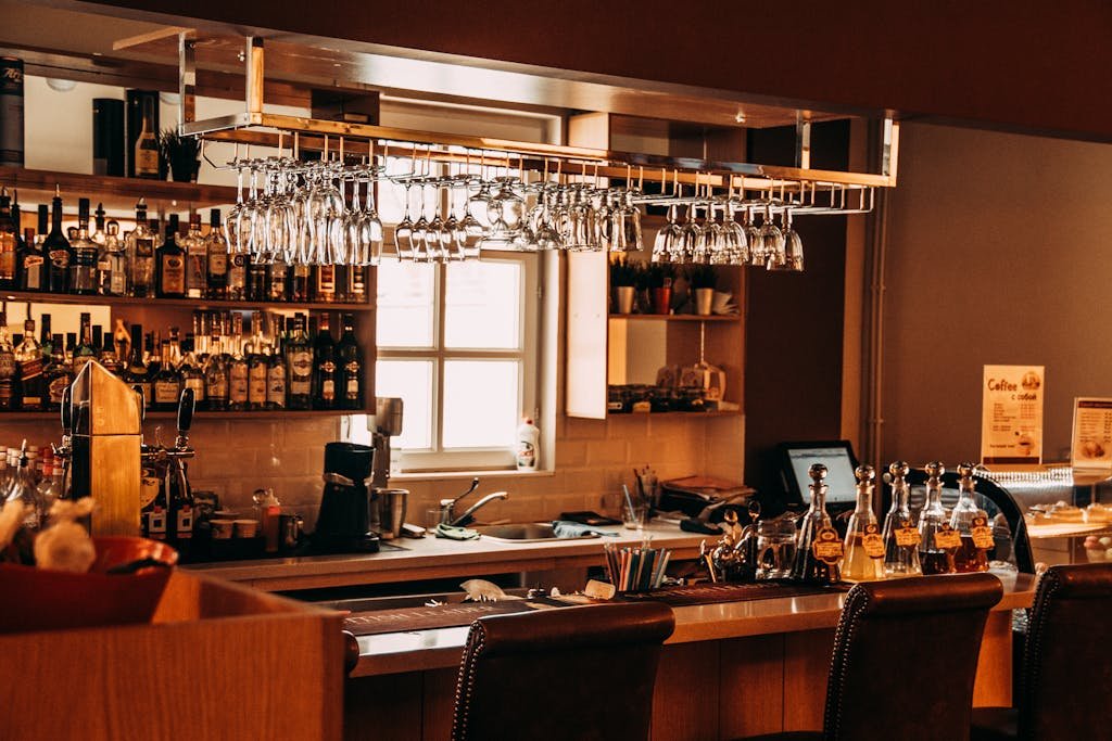 A stylish bar interior featuring hanging glassware, a range of spirits, and wooden furnishings.